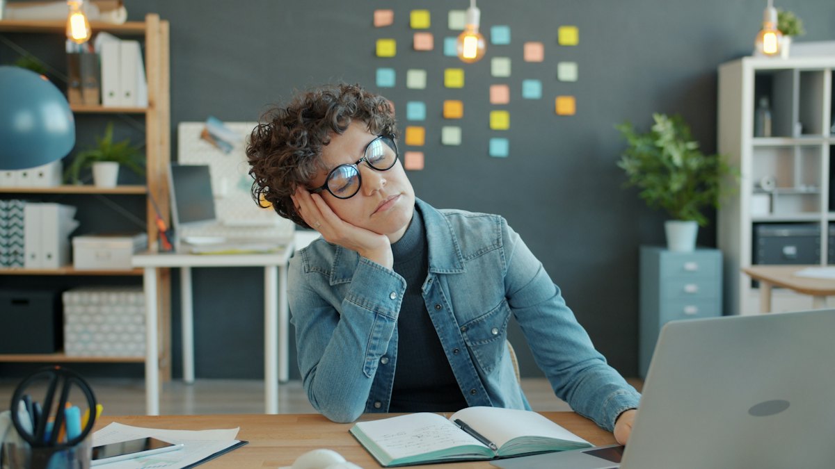 Tired office worker resting her head on her hand at a desk