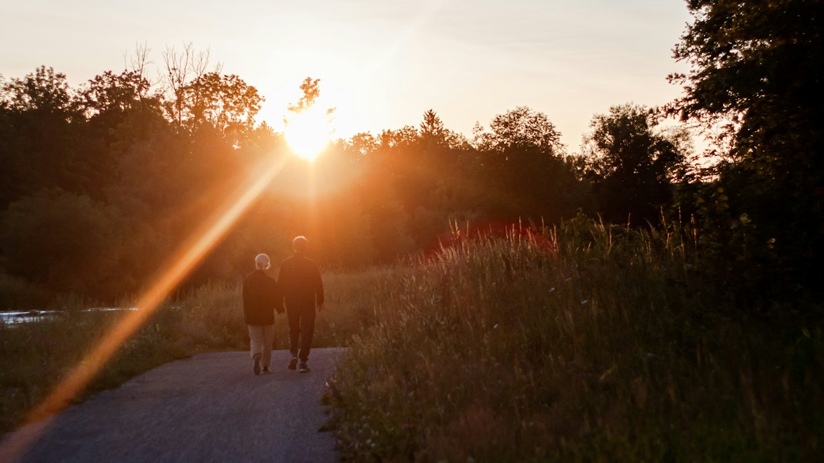 Two people walking along a path at sunset